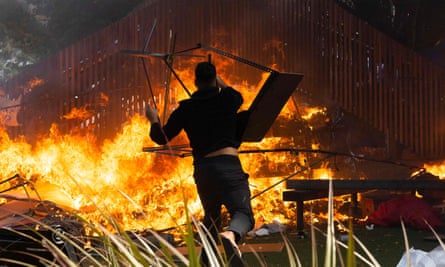 A man throws a desk onto a fire lit at a children’s playground on parliamentary grounds.
