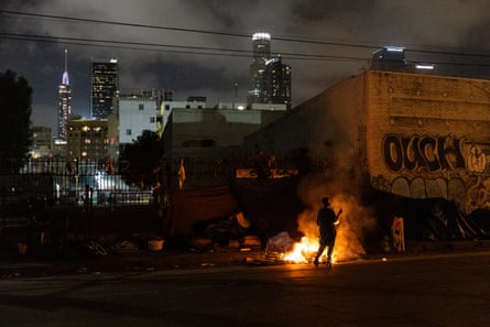 Homeless people keep themselves warm around a fire in Los Angeles, California