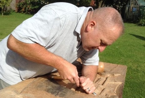Iain Braid carves a piece of wood in his garden.