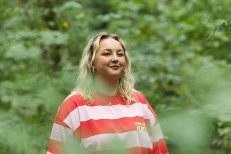 A woman in a pink and red stripy jumper in front of a bush