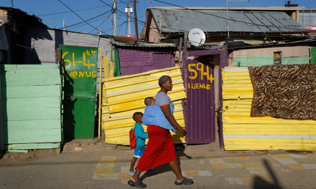 A mother walks her children to school in the Alexandra township of Johannesburg