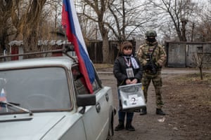 A member of a local election commission, accompanied by a serviceman, visits voters during early voting in Russia’s presidential election in Donetsk, Ukraine