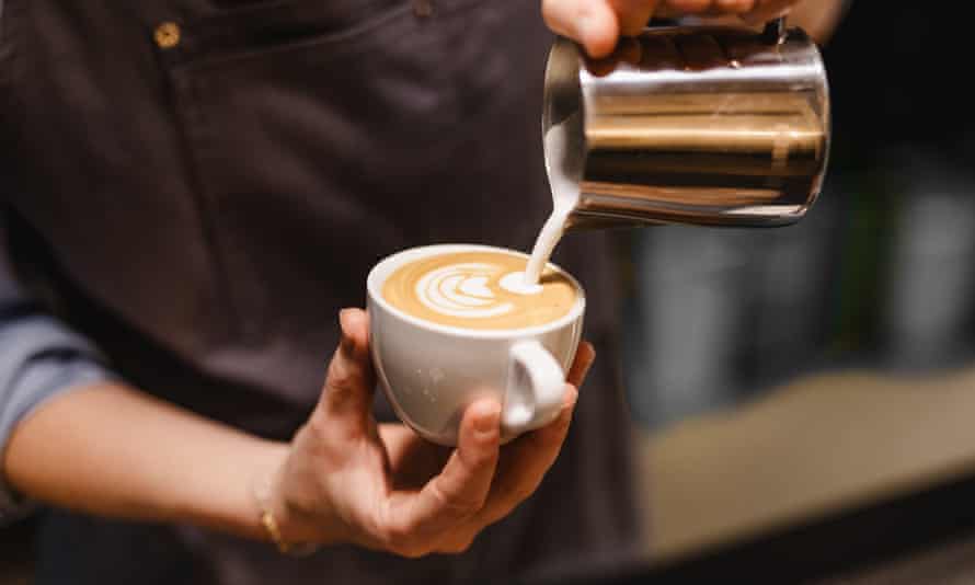 a barista pours a frothy coffee