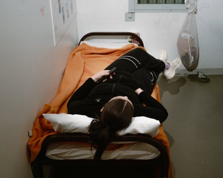 A girl lies on a bed in a cell