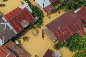 People on a boat make their way through a street flooded due to torrential rains in Aceh Tamiang.