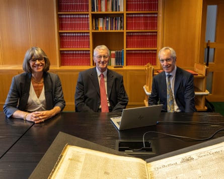 Hilary Benn, Rebecca Lawrence and Richard Hall smie for the camera as they sit before a laptop and bound copies of the Belfast News Letter