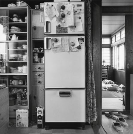 Black and white image of a fridge freezer in a cluttered kitchen