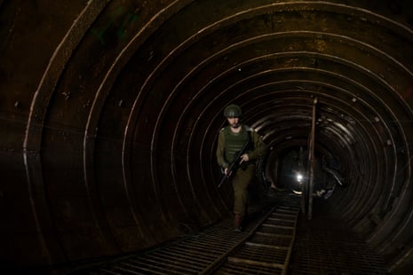 A soldier moves through a dark tunnel holding a gun