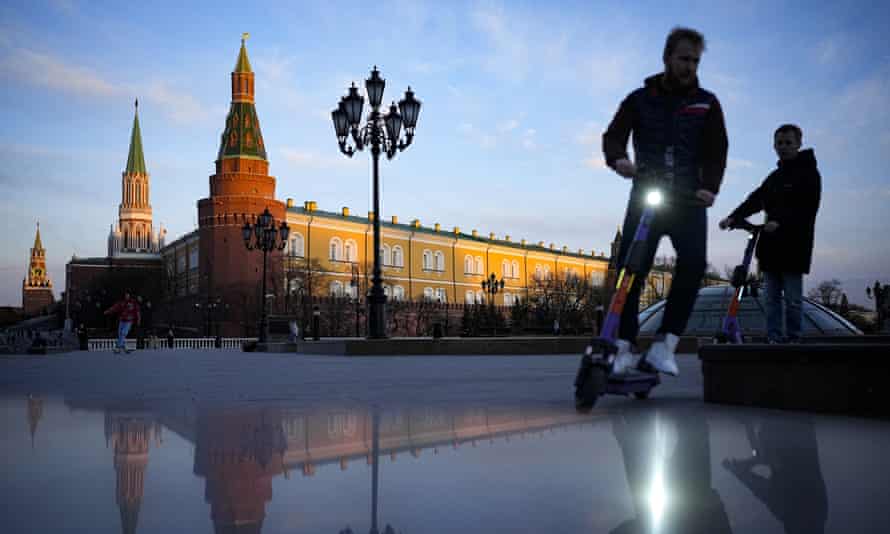 Los hombres montan scooters cerca de la Plaza Roja y el Kremlin después del atardecer en Moscú, Rusia