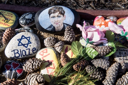 A pile of pinecones, rocks with the name “Blaze” and a star of David painted on them, and one with a painting of a young man on it, with flowers.