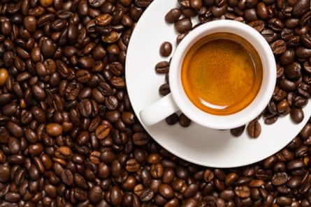 Cup of espresso with coffee beans on saucer, on a bed of coffee beans