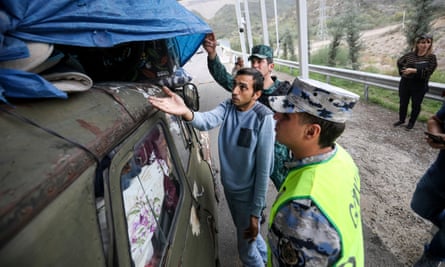 An ethnic Armenian resident of Nagorno-Karabakh shows his belongings to an Azerbaijani border guard at the Lachin checkpoint on the way to Armenia