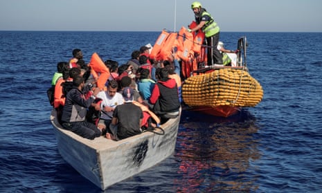 Crew members of an NGO rescue ship give lifejackets to migrants on an overcrowded boat in the Mediterranean Sea in October 2022.