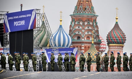 Russian soldiers standing on Red Square where a banner on a stage reads: ‘Donetsk, Luhansk, Zaporizhzhia, Kherson – Russia!’