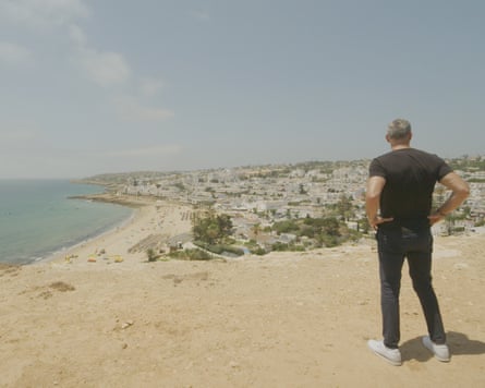 Man overlooks seaside town from sand dune