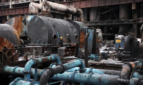 A worker looks up as they repair equipment at a thermal power plant damaged in an earlier missile attack