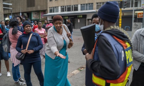 A woman waiting for a taxi pleads with a police officer to let taxi operators drive in Johannesburg on 29 March. Some drivers were missing a permit to operate during South Africa’s lockdown.