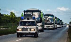 Police escort a convoy of buses carrying tourists evacuated from Caibarien.
