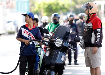 A worker fills a motorbike with fuel at a filling station