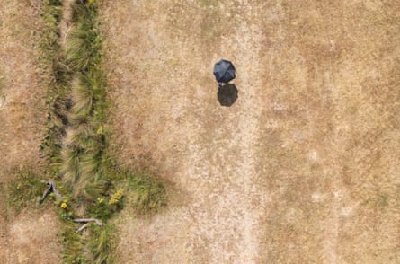 Top-down drone shot of person walking under an umbrella