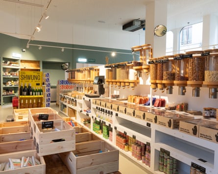 Interior of a vegan shop with bulk food dispensers, wooden crates, and shelves of jars