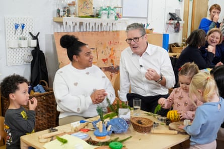 Keir Starmer sitting at a low table with three young children and a carer.