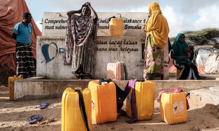 Women fill jerrycans with water from a well. In Somalia, where cholera outbreaks have killed hundreds of people, the looming famine threatens 6.2 million people, more than half the population