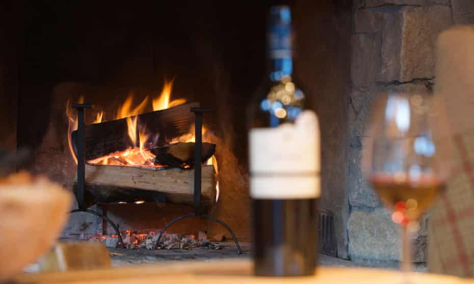 Glass of wine and bottle by fireplace