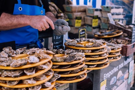 Oyster farmer shucking fresh oysters at a market stall
