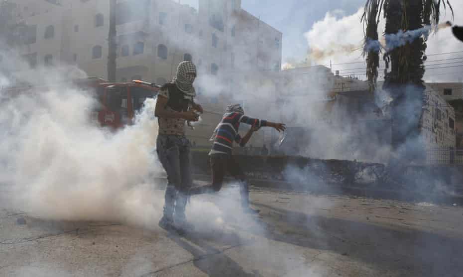 A Palestinian protester hurls back a teargas canister fired by Israeli troops during clashes in the West Bank city of Hebron.