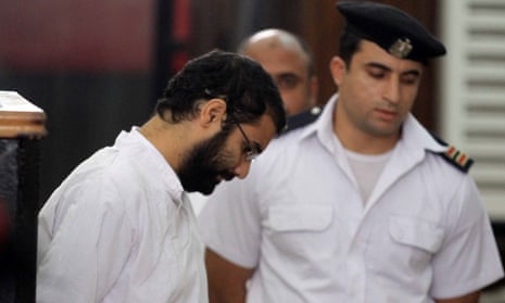 Activist Alaa Abd el-Fattah stands in front of a police officer at a court