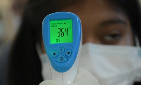 Travellers have their temperature checked at an airport in India. 