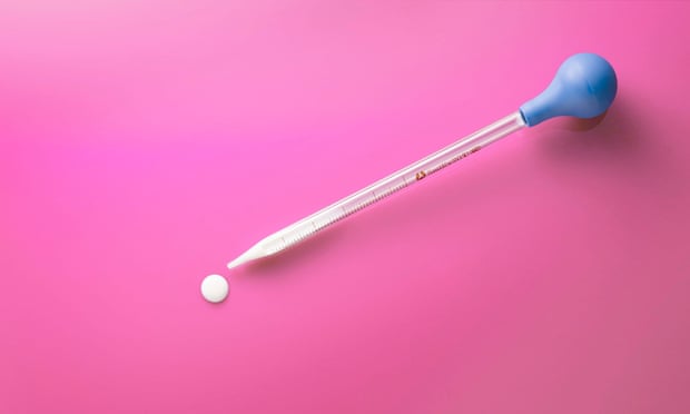 Pipette against pink background, with drop of milk squeezed out of it