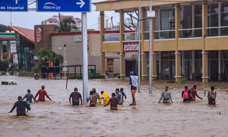 Mostly men walking waist-high brown water.