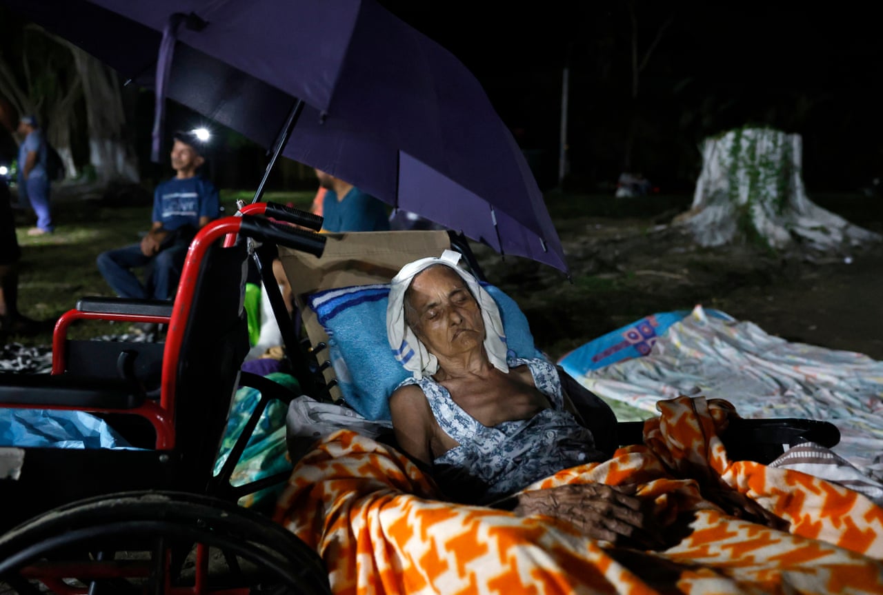 An elderly woman lies in makeshift bed