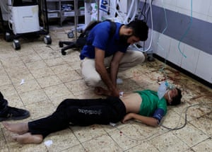 graphic content. A man lies on the floor of a hospital being attended to by a medic in Khan Younis, Gaza.