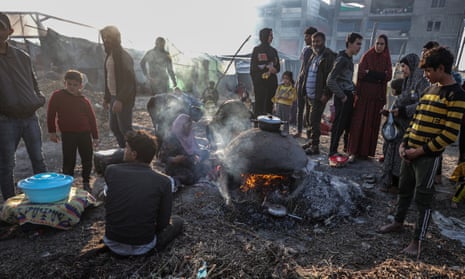 Displaced Palestinian prepare a meal on empty land where they set up makeshift tents in Rafah, southern Gaza