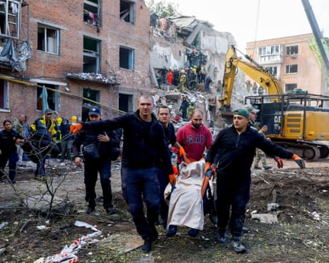People carry a casualty, as emergency services work to rescue residents from under the debris at the site of an apartment building which was hit by a Russian missile strike in the town of Pryluky in the Chernihiv region, Ukraine.