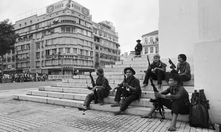 Group of North Vietnamese soldiers with their weapons sitting on steps smoking in a square in central Saigon