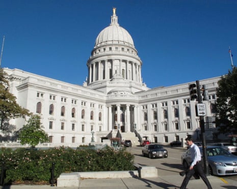 Man walks by two-winged white stone building.