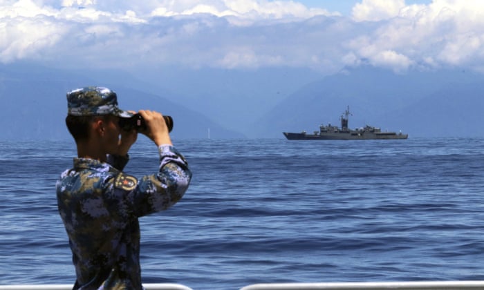 In this photo provided by China’s Xinhua News Agency, a People’s Liberation Army member looks through binoculars during military exercises on Friday. Taiwan’s frigate Lan Yang is seen at the rear.