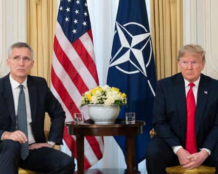 A photograph of Jens Stoltenberg sitting beside Donald Trump, with the US and Nato flags hanging behind them. Both are looking to the right.