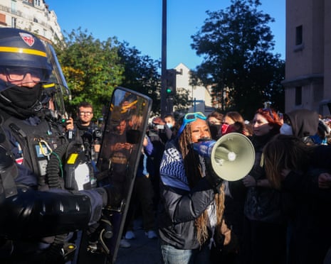 A protester uses a megaphone next to French CRS riot police outside Lycee Helene-Boucher high school, during nationwide protests in Paris, France.