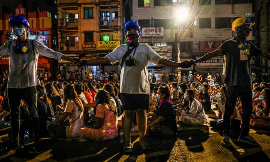 Protesters hold hands to keep watch during a night-time demonstration against the military coup in Yangon