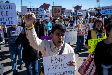 People chanting, raising their fists, and holding signs as they march together.