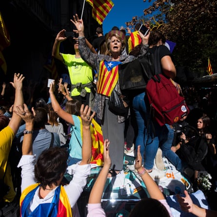 People demonstrate on a Spanish Guardia Civil car as officers search the Catalan vice-president’s office in Barcelona