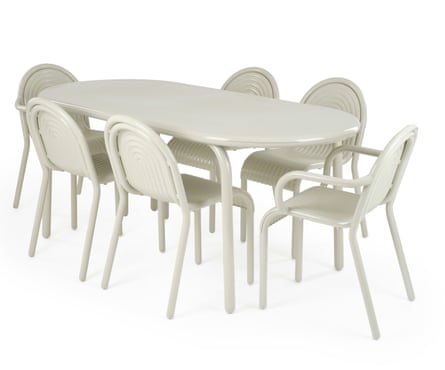 A rounded edge off-white metal table is surrounded by 6 off-white metal chairs that have arched shape backs and rounded arms.