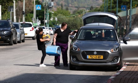 A woman and a girl hold pet boxes beside a car with its doors open