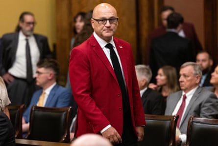 a man in a red blazer walks in a room