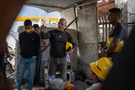 Men in hard hats stand in a circle and talk